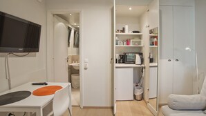 A compact living space with a kitchenette, a dining area, and a TV mounted on the wall.