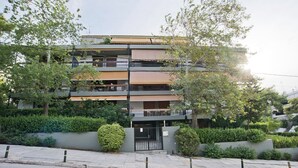 A multi-story residential building with balconies, surrounded by greenery.