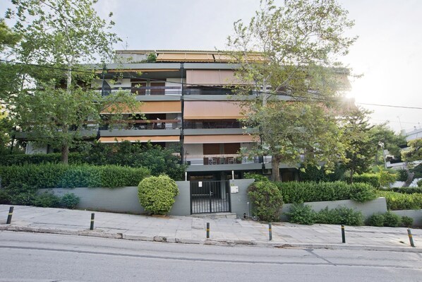 A multi-story residential building with balconies, surrounded by greenery.