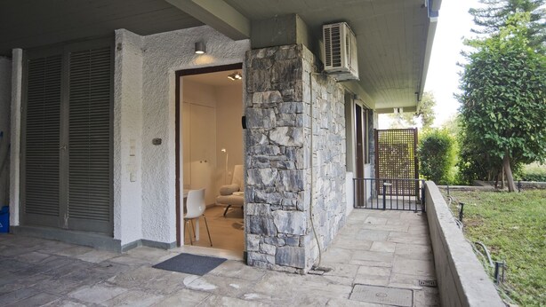 A stone exterior wall, a covered porch, and a small outdoor seating area.