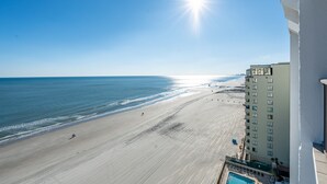 A beach view from a hotel balcony with a pool, ocean, and a high-rise building. - Upscale Oceanfront 3BR Condo • 14th Floor • Golf Course Views (Myrtle Beach)