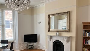 Una sala de estar con chimenea, televisor, estantería y candelabro.