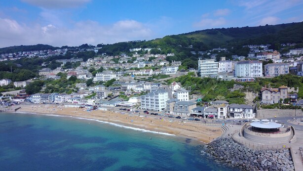 Un pueblo costero con playa, edificios y un litoral rocoso.