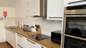 Una cocina moderna con armarios blancos, encimera de madera, estufa integrada y horno.