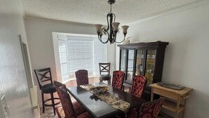 Comedor con mesa de madera oscura, sillas rojas con estampado, candelabro y aparador de madera con puertas de cristal.