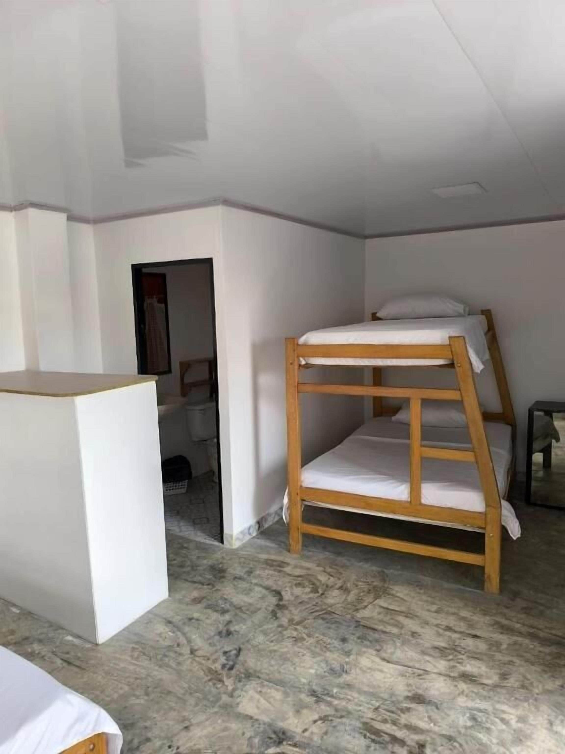 A room with a bunk bed, a small table, and a wardrobe.