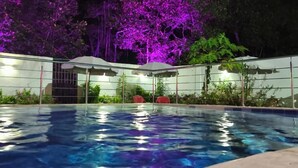 Une piscine à l’eau d’un bleu limpide, entourée d’une zone abritée par un toit.