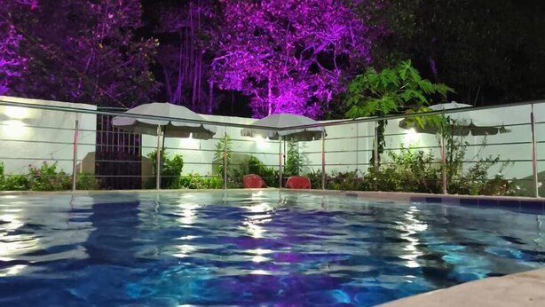 Une piscine à l’eau d’un bleu limpide, entourée d’une zone abritée par un toit.