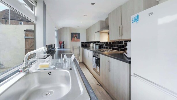 Una cocina moderna con un lavamanos de acero inoxidable, estufa y armarios blancos.