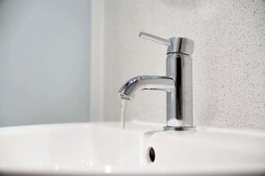 A modern bathroom sink with a chrome faucet and running water.
