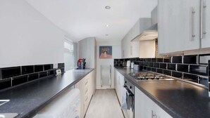 Una cocina moderna con encimeras negras, electrodomésticos de acero inoxidable y armarios blancos.