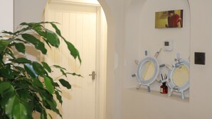 A bathroom with two round mirrors, a small sink, and a wall-mounted light switch. - Acaccia Bunglow  (Carterton)