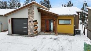 A two-story building with a garage, stone facade, and a yellow exterior.