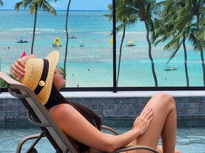 A woman relaxing by a pool with a view of the ocean and palm trees. - MAKADAMIA 103 (Ipojuca)