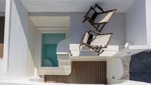 A covered outdoor area with a wooden deck, a white wall with a teal accent, and a stone wall.