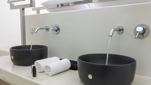 A bathroom with two black sinks, each with a faucet, and a towel dispenser. - Santorini Sun Villa Two in Oia | Private Hot Tub (Oia)