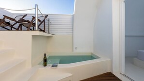 A small outdoor hot tub area with steps leading up to it, a bottle of wine, and a glass on the steps. - Santorini Sun Villa Two in Oia | Private Hot Tub (Oia)