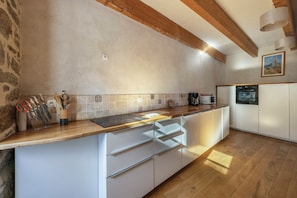 Een keuken met houten balken, een betegelde spatwand en witte kasten.
