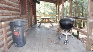 A covered wooden deck with a picnic table and a barbecue grill. - Cozy Log Cabin in Cook Forest ~ Dog Friendly (Clarington)