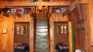 A cabin interior with a wooden staircase, two beds with plaid bedding, and a sign indicating 'Cabin #5'. - Cozy Log Cabin in Cook Forest ~ Dog Friendly (Clarington)