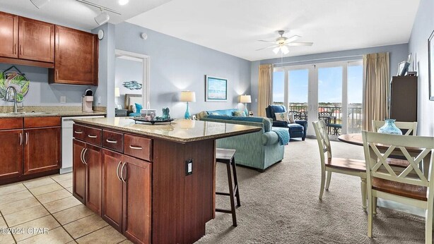 A modern kitchen with wooden cabinets, a central island, and a dining area with a table and chairs. - Ease, Comfort and Tranquility at Lake Town Wharf Resort, Panama City Beach, FL (Panama City Beach)
