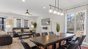 A spacious living room with a dark wooden dining table, black leather chairs, a leather sofa, and a ceiling fan. - 3 Stry Treehouse Chickamauga 20 min to Chatt Vistas (Walker County)