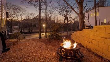 A backyard with a fire pit, a brick wall, and a house in the background.