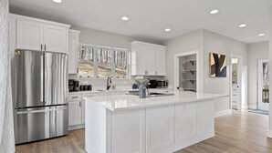 A modern kitchen with white cabinetry, stainless steel appliances, and a large island. - 3 Stry Treehouse Chickamauga 20 min to Chatt Vistas (Walker County)