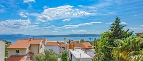 Un pueblo costero con edificios de tejas color terracota, cielo despejado y vista al mar.