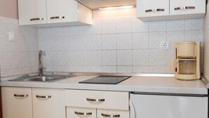 A kitchen with white cabinets, a stainless steel sink, a coffee maker, and a patterned backsplash. - Beachfront Crikvenica Apartments with Sea View - Standard Studio Apartment with Sea View (Crikvenica)
