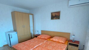Une chambre à coucher comprenant un lit, une armoire, un bureau, une chaise et un appareil de climatisation.