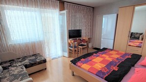 Una camera d'albergo con un letto, una scrivania con una sedia, una televisione e un armadio.