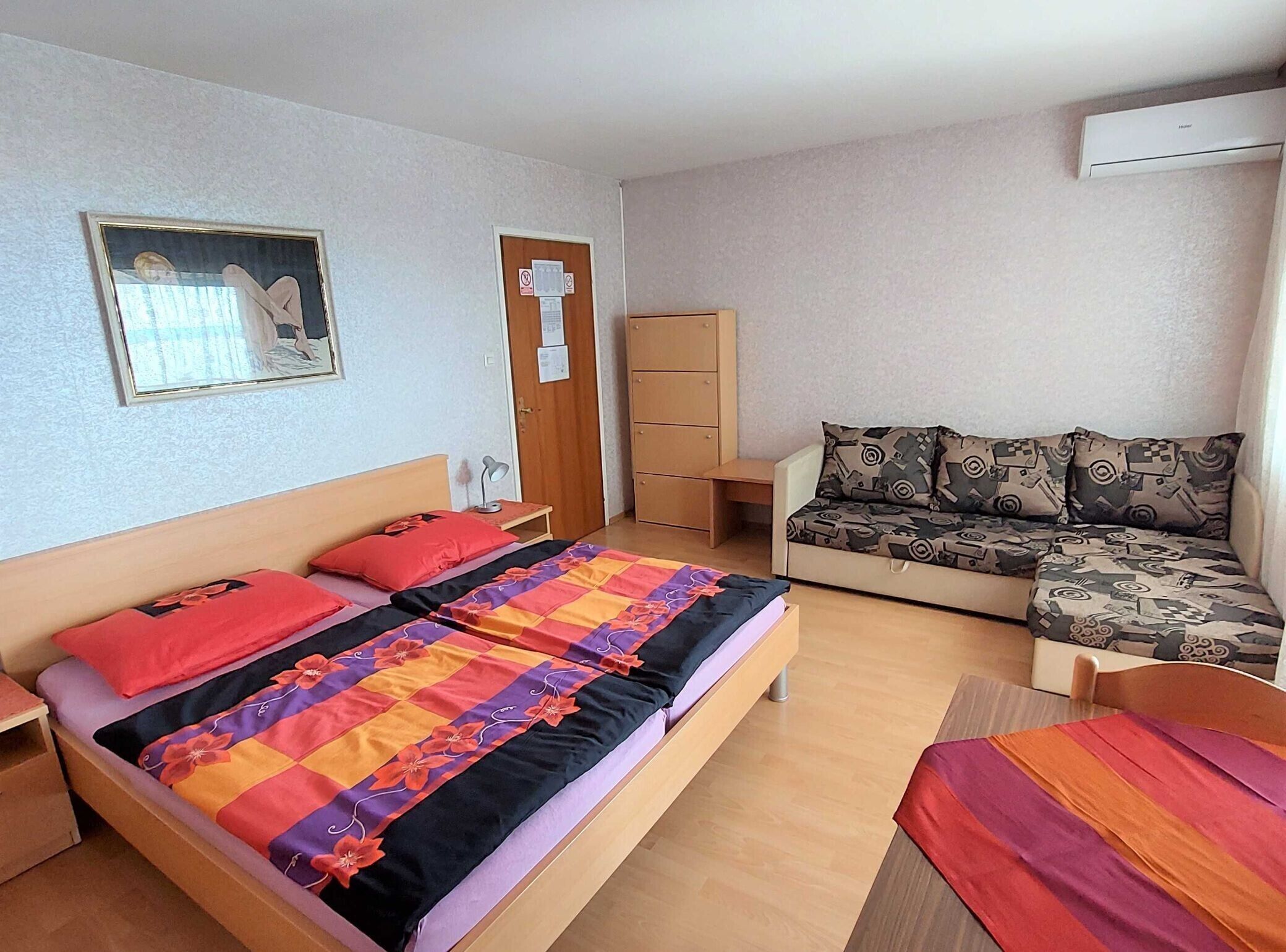 Ein Schlafzimmer mit einem Bett, einem Schlafsofa, einem Schreibtisch und einem Kleiderschrank.