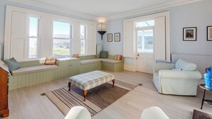 A room with a large window seat, a white sofa, and a patterned rug. - Derwas is a beautiful space for up to eleven guests to call home. (Colwyn Bay)