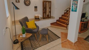 Una sala de estar con un sofá, una mesita, una lámpara de pie y una escalera.