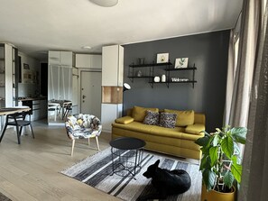 Relax in this stylish living space with a sofa, armchair, and potted plant, perfect for unwinding.