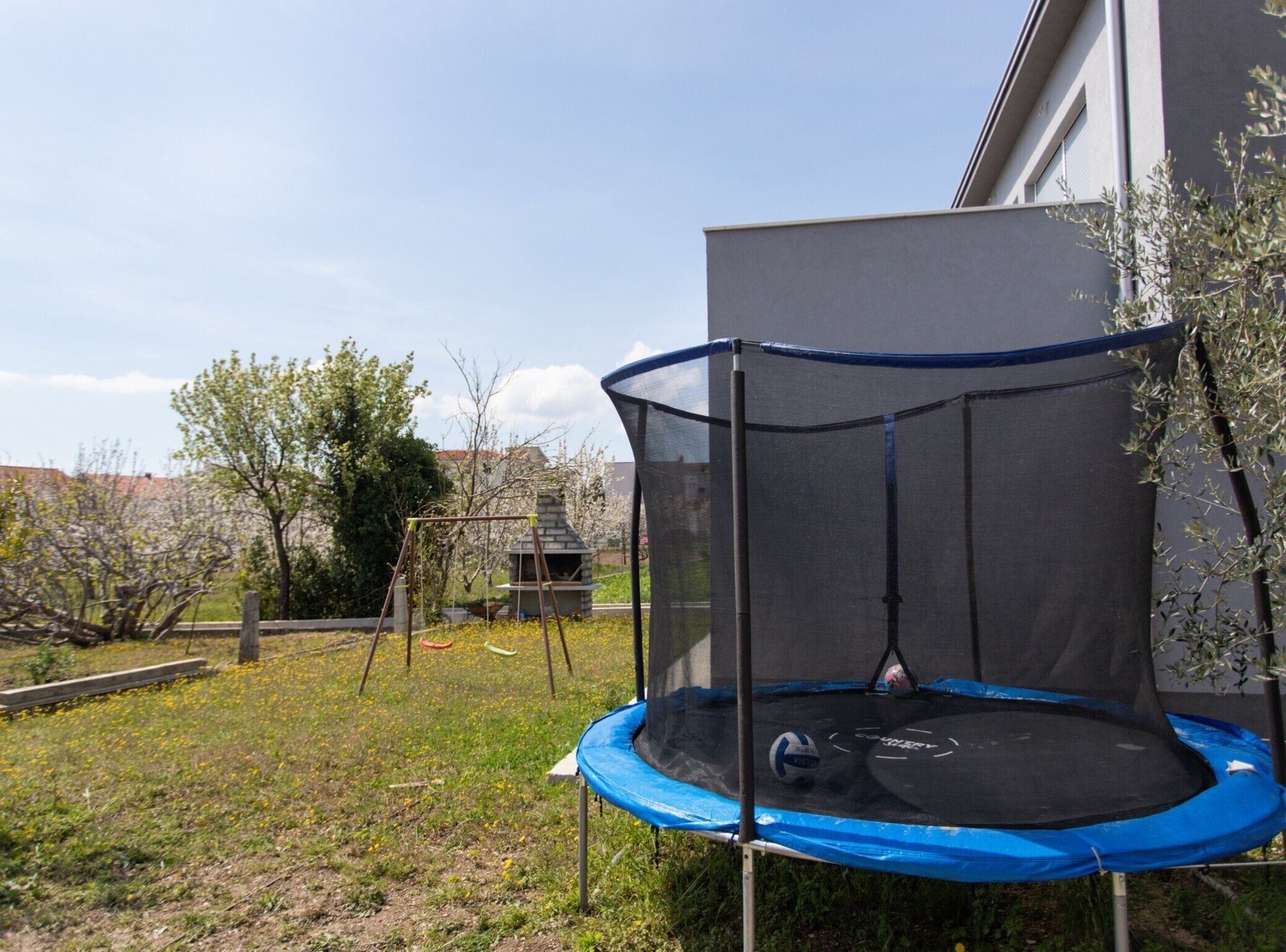 Un trampolino in un giardino sul retro con un caminetto in pietra e un'altalena.