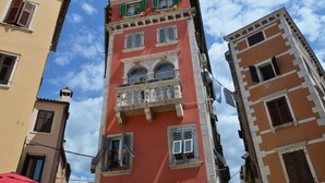Un edificio a più piani con balconi, facciata rossa e persiane tradizionali.