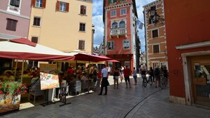 Una strada animata con tavoli all'aperto e diversi edifici.