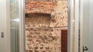 Un ingresso che dà su una stanza con parete in pietra e porta in legno.