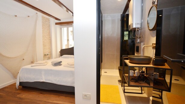 Una camera da letto con un letto, un bagno con lavandino e specchio, e una zona doccia.