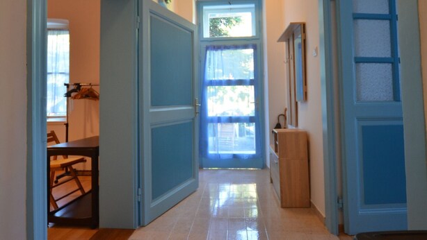 Un pasillo con una puerta que da a una habitación con ventana, una mesita y un armario.