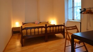 Un dormitorio con una cama de madera, lámparas de noche, una ventana y una silla.