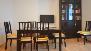 Un comedor con una mesa, sillas, un televisor y una estantería.