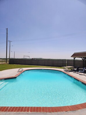 A clear blue swimming pool with a brick edge, surrounded by a wooden deck and outdoor furniture. - The Lodge (Bridgeport)