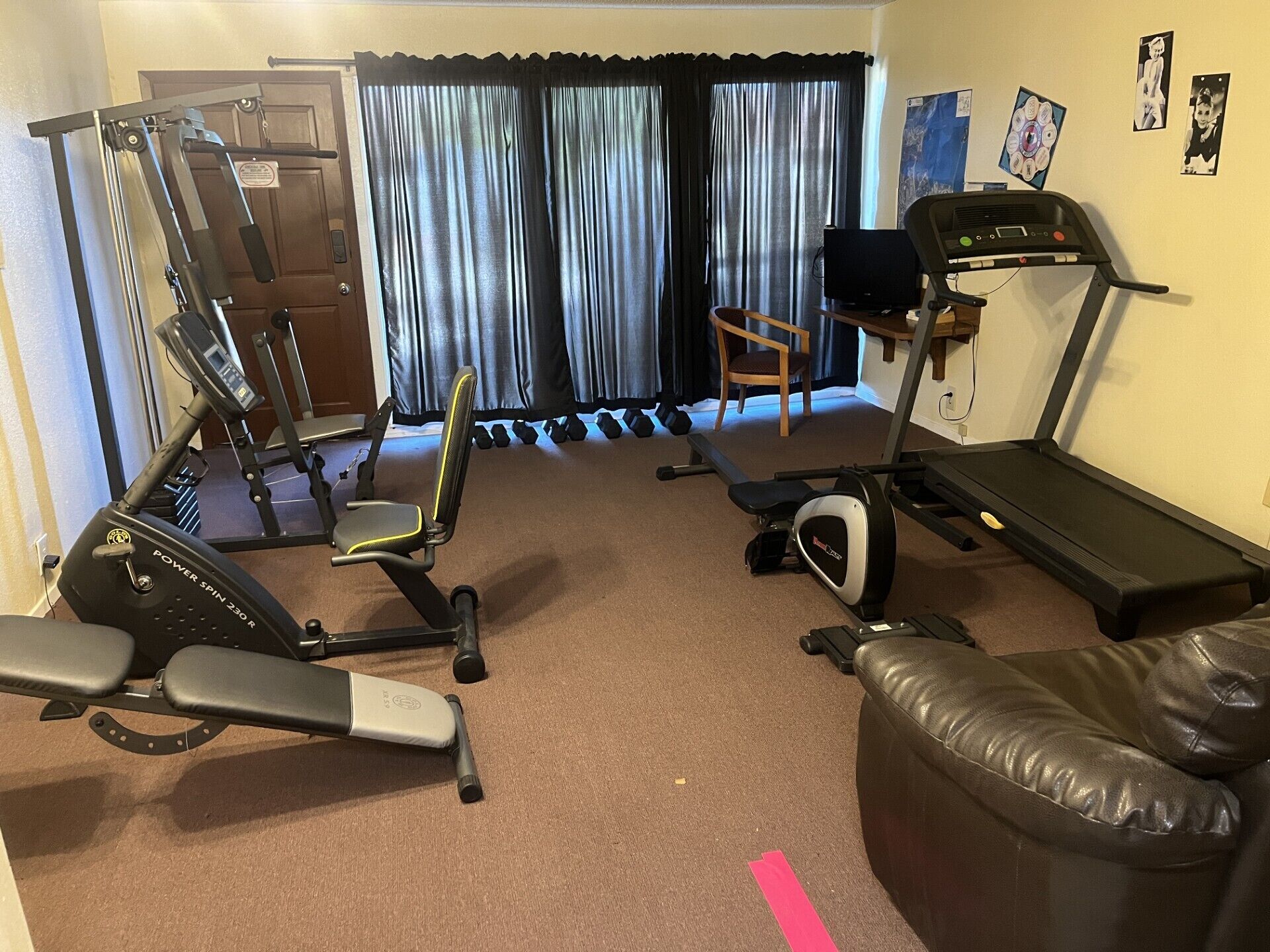 A home gym with a treadmill, stationary bike, and exercise equipment.