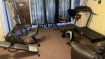 A home gym with a treadmill, stationary bike, and exercise equipment.