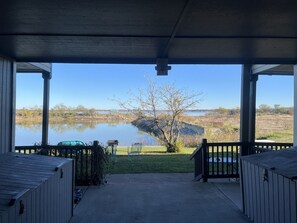 A covered porch with a view of a lake and grassy area. - The Lodge (Bridgeport)