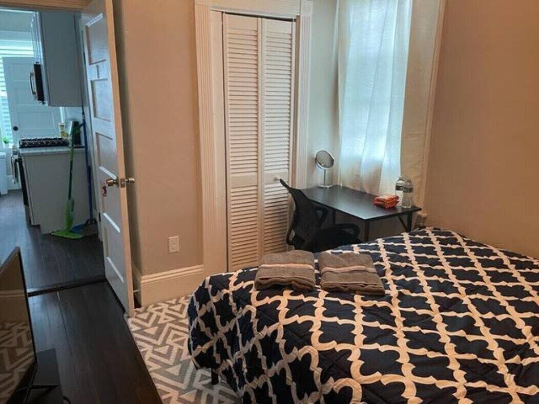 Quarto com cama, escrivaninha, cadeira e porta para um banheiro.