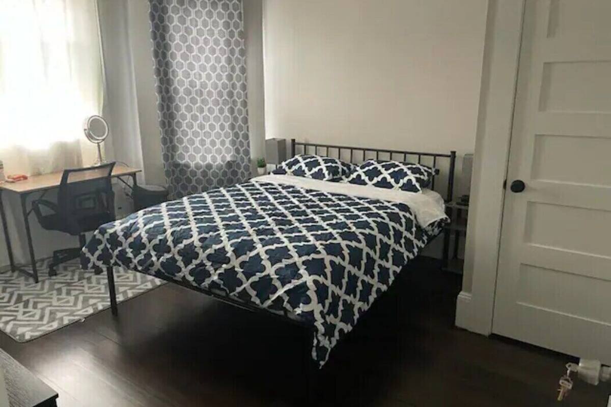 A neatly arranged bedroom with a bed, a desk, and a chair.
